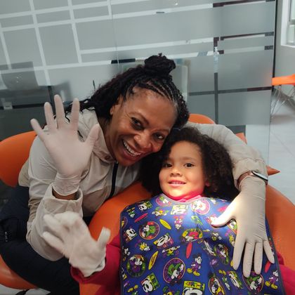 Dentista examinando los dientes de un paciente con un espejo dental y luz en una clínica.