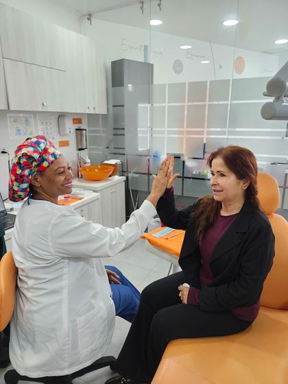 Dentista examinando los dientes de un paciente con un espejo dental y luz en una clínica.