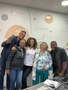 Cinco personas sonriendo y posando juntas en una sala de reuniones con una pizarra blanca detrás.
