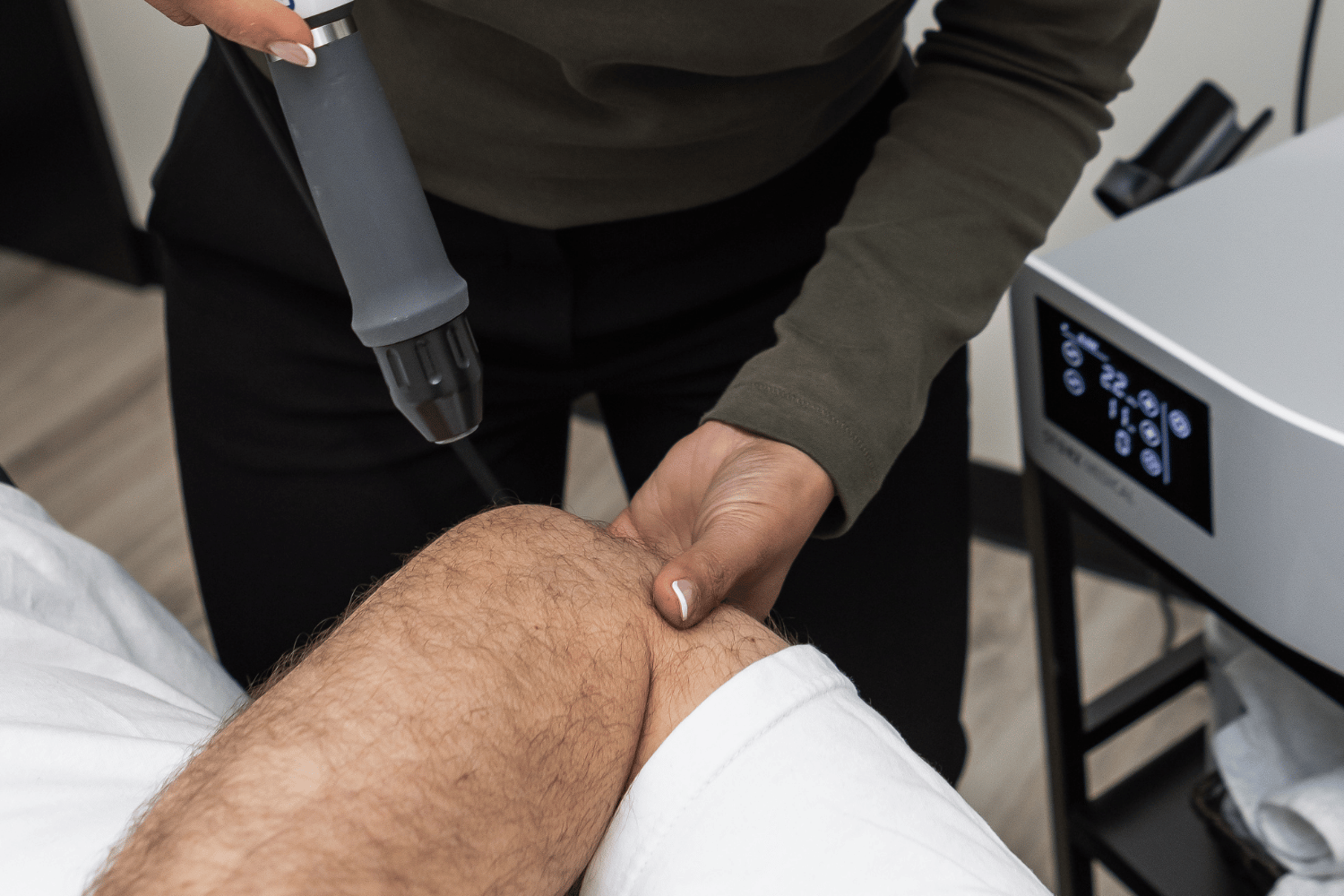 Physiotherapist applying shockwave therapy to a patient's heel at Asana Physiotherapy in Maple Ridge