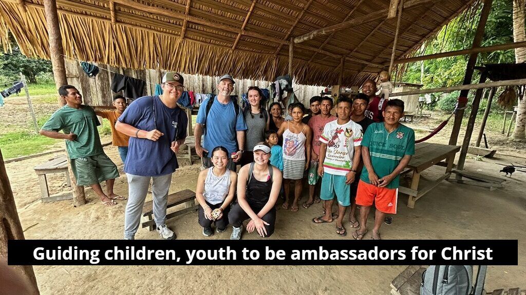 A group of people are posing for a picture in front of a hut.