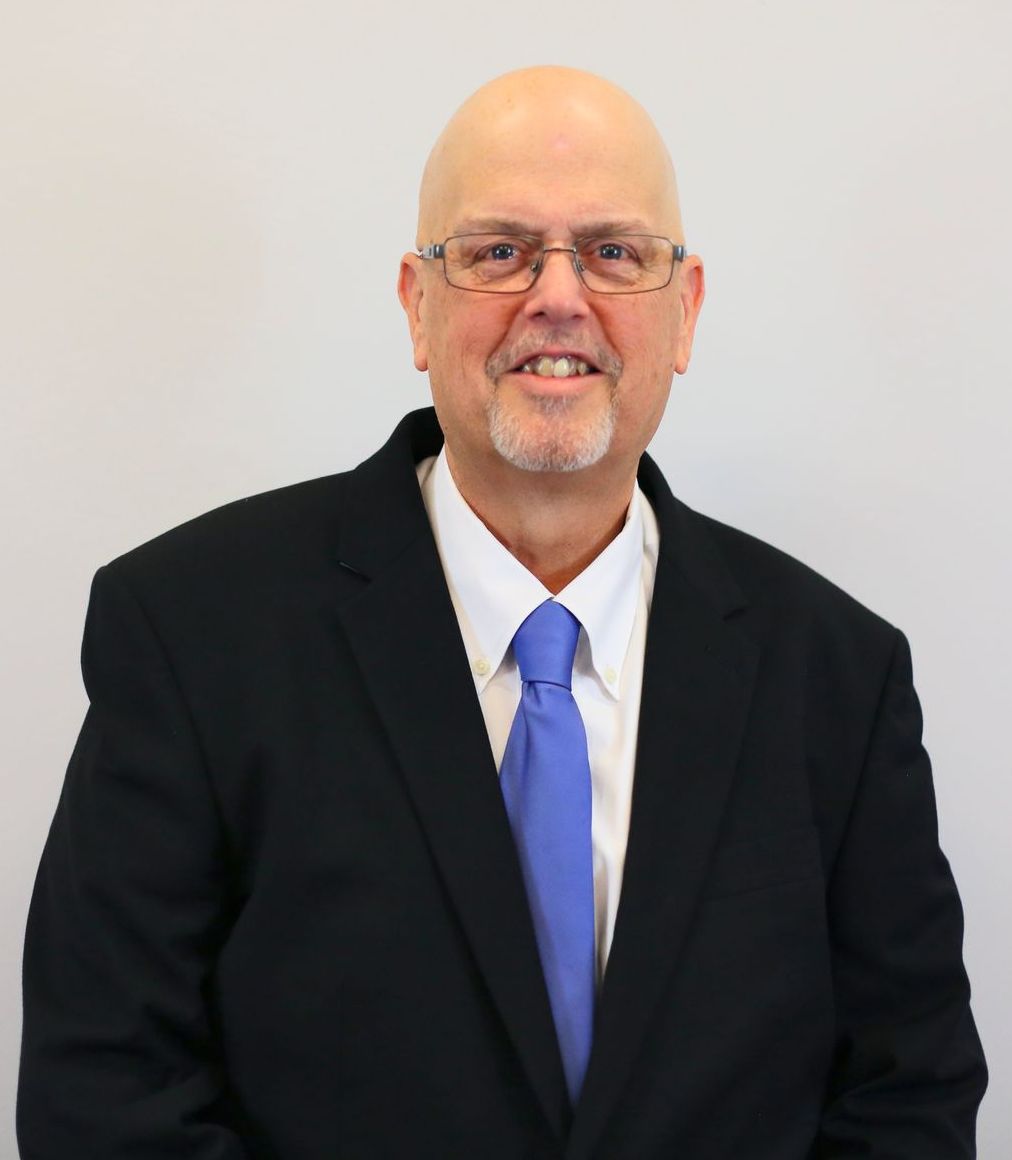 A man in a suit and tie is smiling for the camera