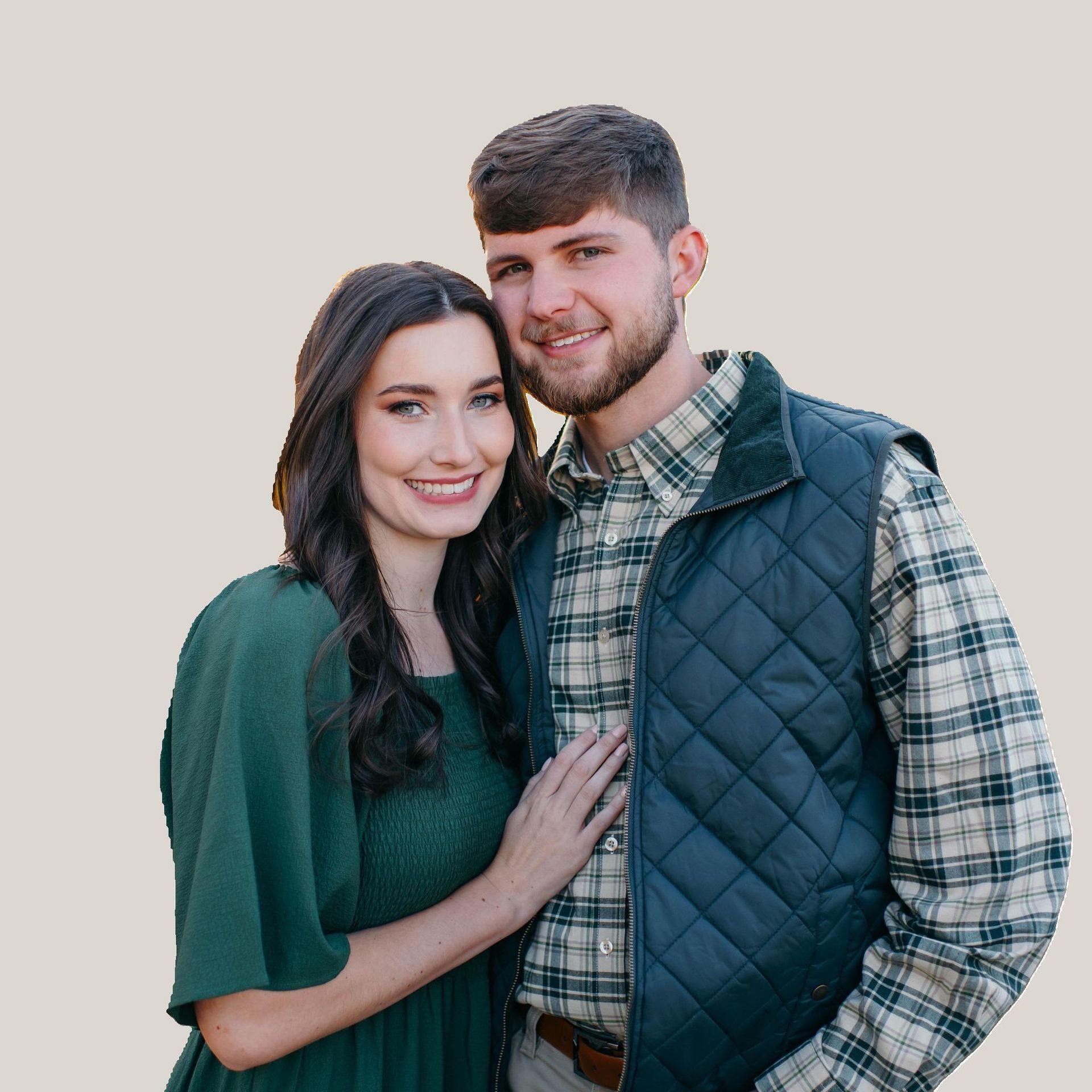 A man and a woman are posing for a picture and the woman is wearing a green dress