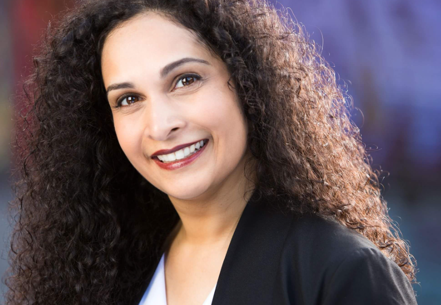 a close up of a woman 's face wearing a pink jacket and smiling .