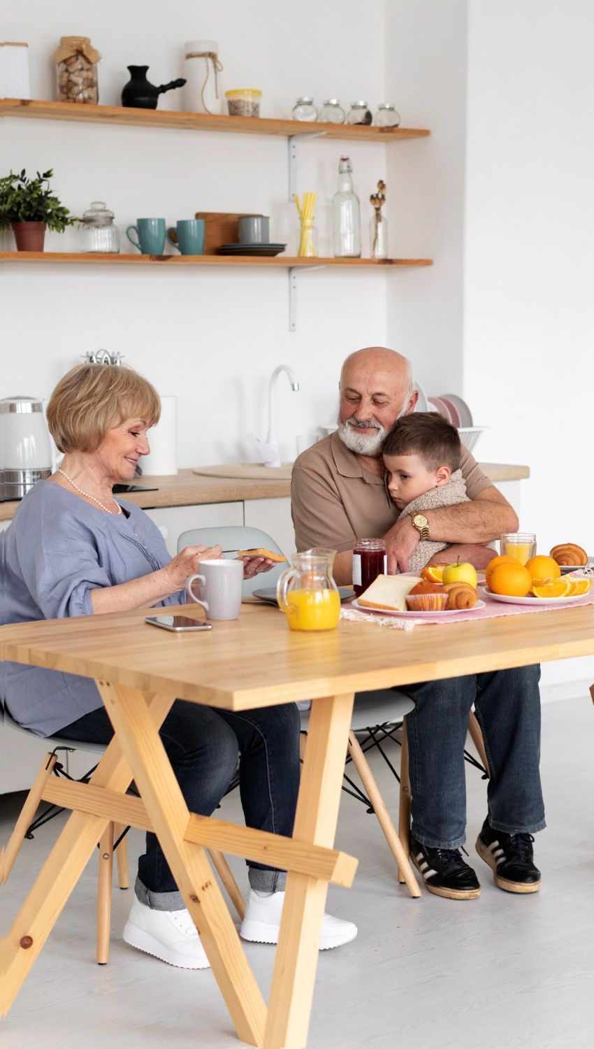 An elderly couple and a young girl are sitting on a park bench.