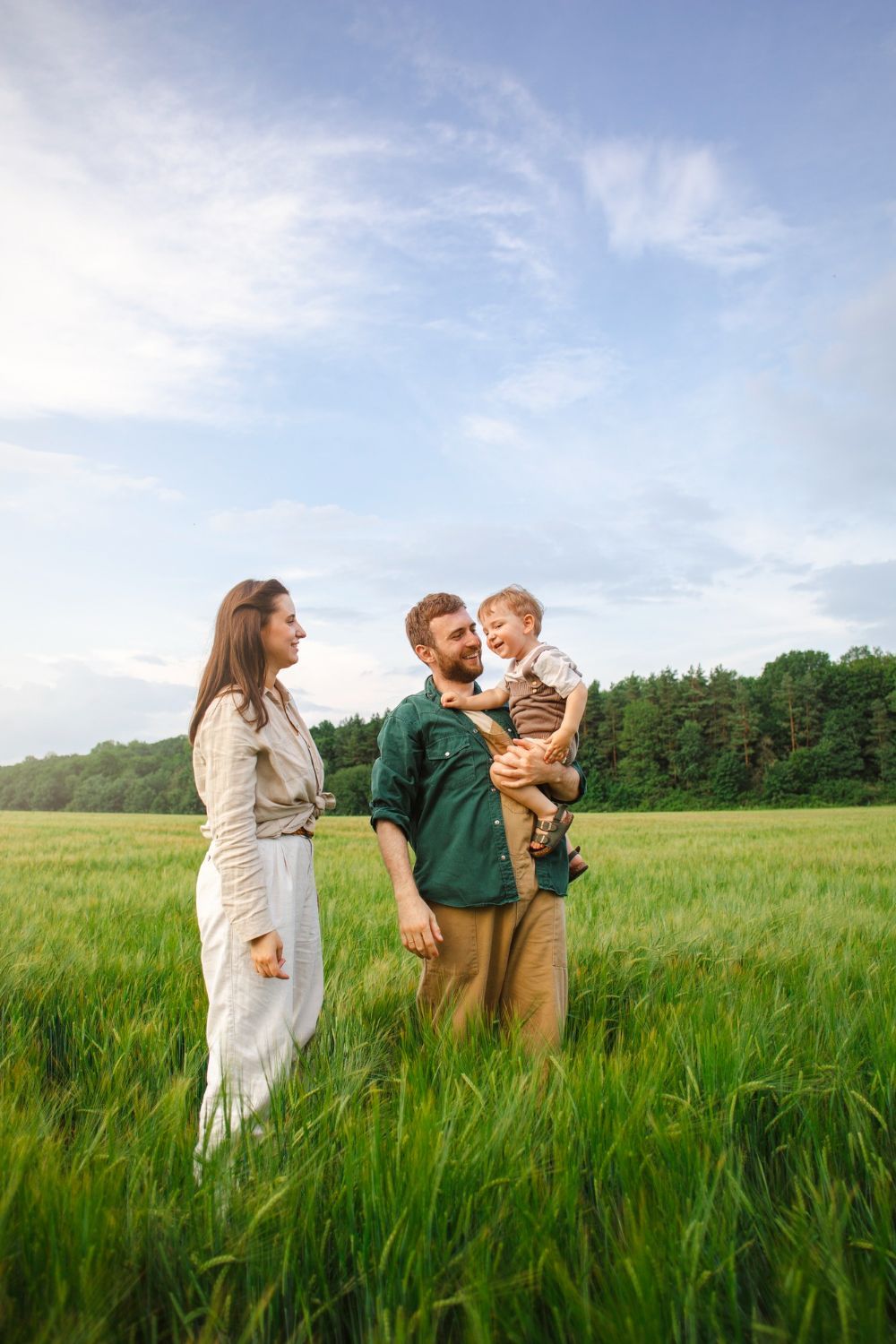 A family is standing in a grassy field holding hands.