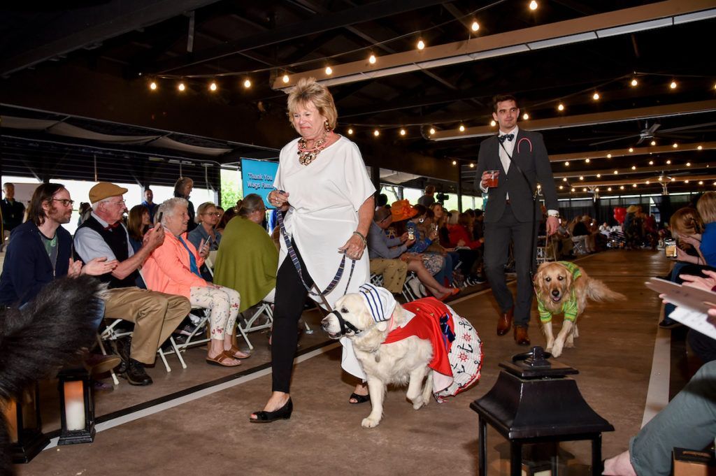 A woman is walking down a runway with two dogs.