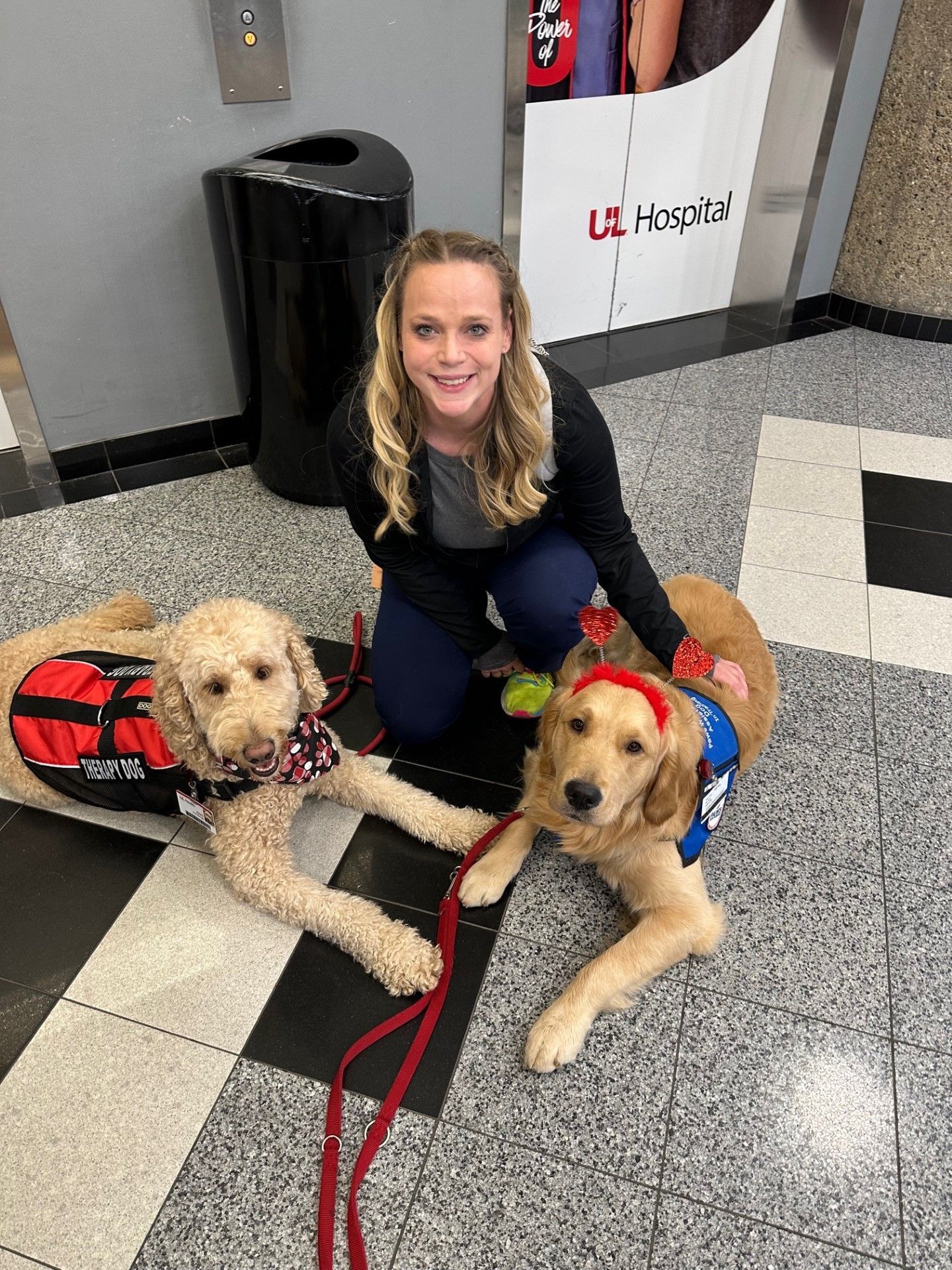 Employee kneeling with Therapy Pets at the Hospital