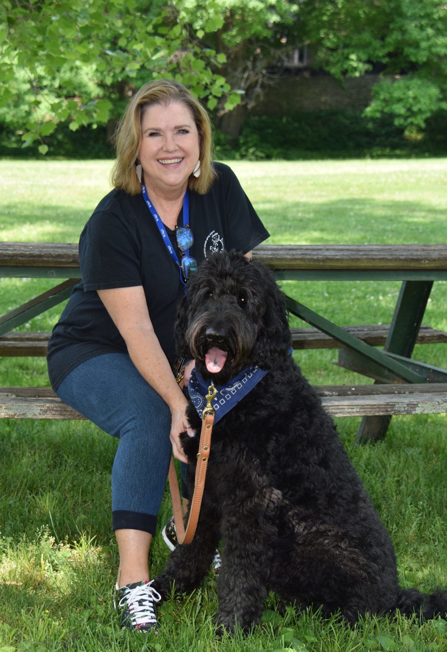 Micki seated on a picnic table with Leo sitting at her feet