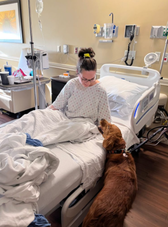 Patient sitting up in bed to pet a golden retriever