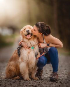 Girl stooping to kiss her golden Retriever