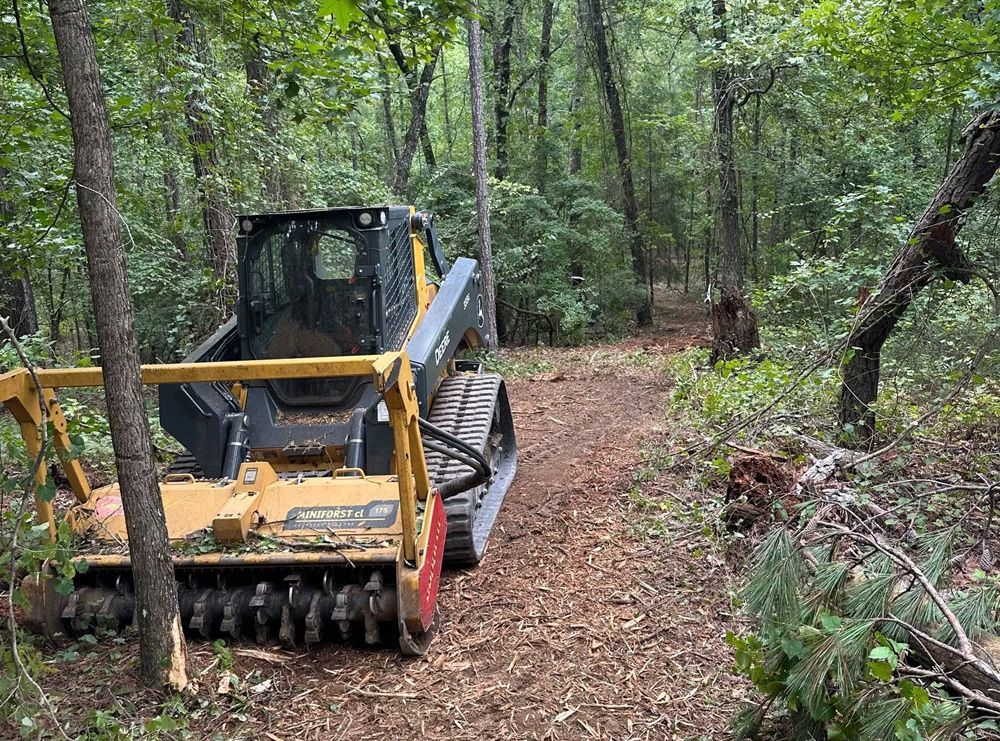 A bulldozer is driving down a path in the woods.