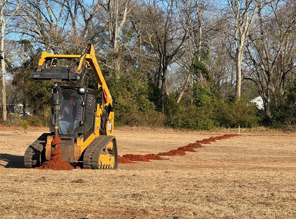 A yellow bulldozer is digging a trench in a field.