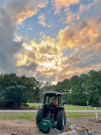 A tractor is parked in a field with a cloudy sky in the background.