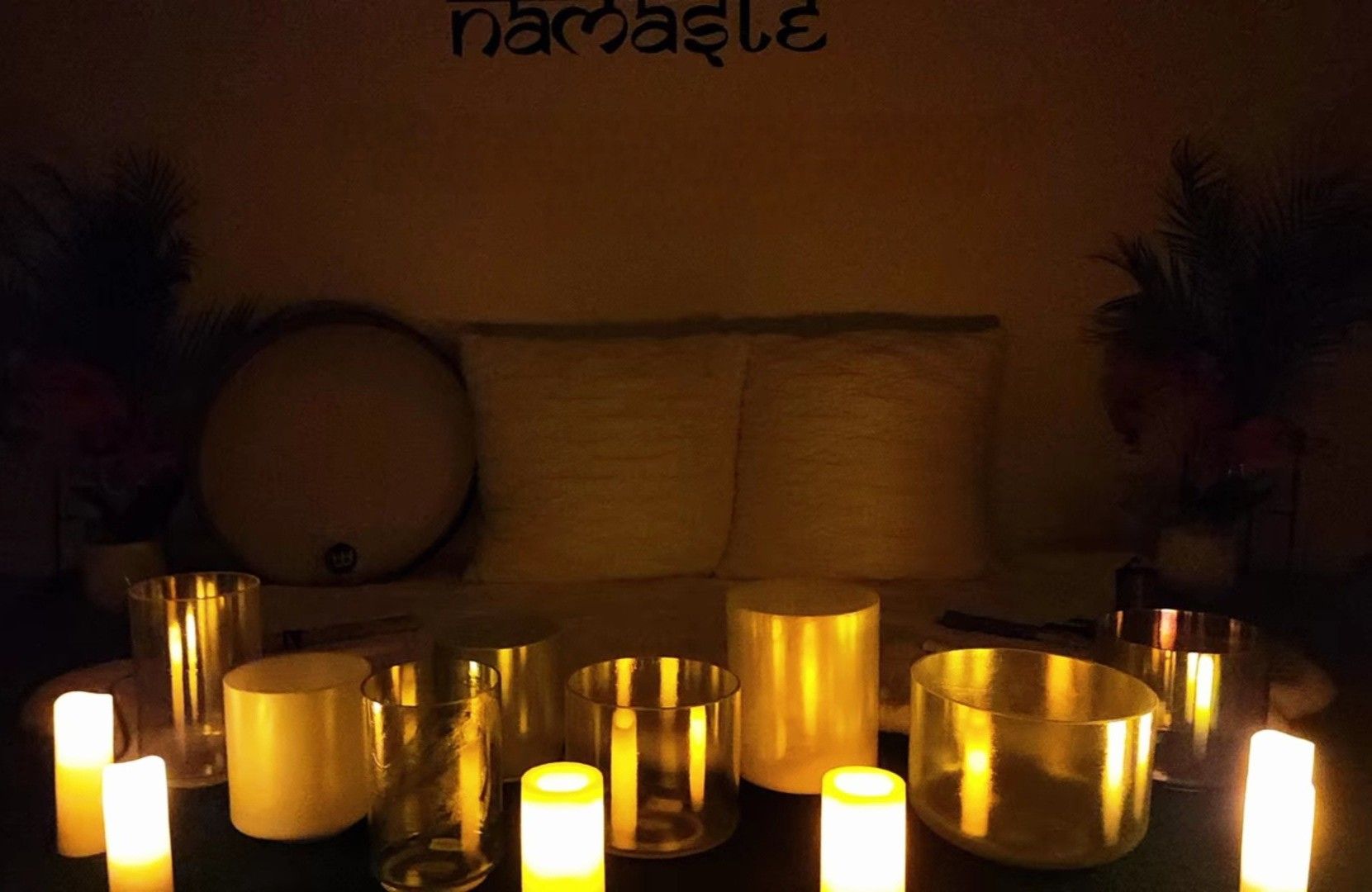 A woman is laying on a yoga mat with candles around her.