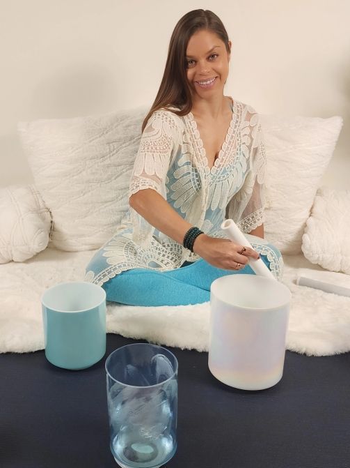 A woman is sitting on a couch holding a bowl and a glass of water.