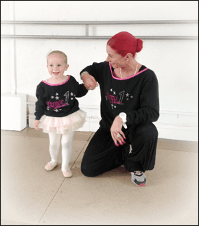 woman crouching next to a young girl wearing a ballet outfit with a white wall behind
