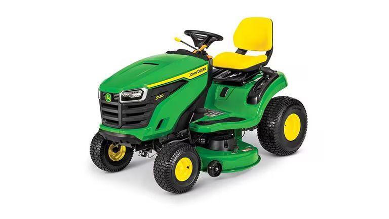 A John Deere S120 riding lawn mower with a green frame, black grill, and yellow seat on a white background.