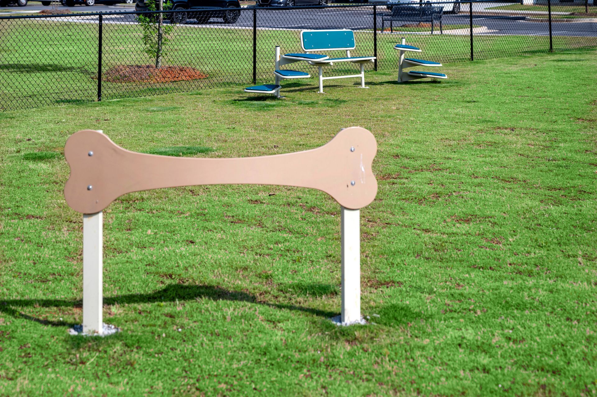 A dog park with a large bone in the middle of the grass.