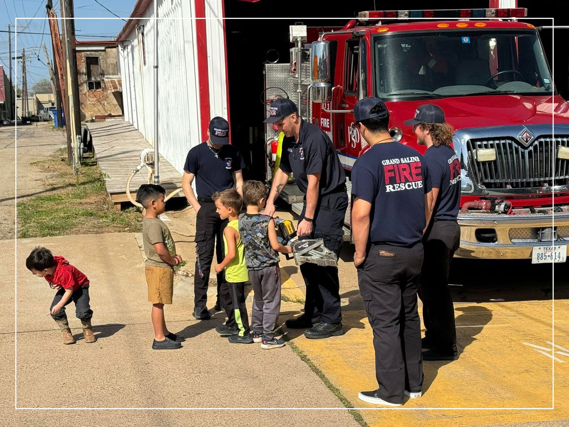 A group of firefighters and children are standing in front of a fire truck.