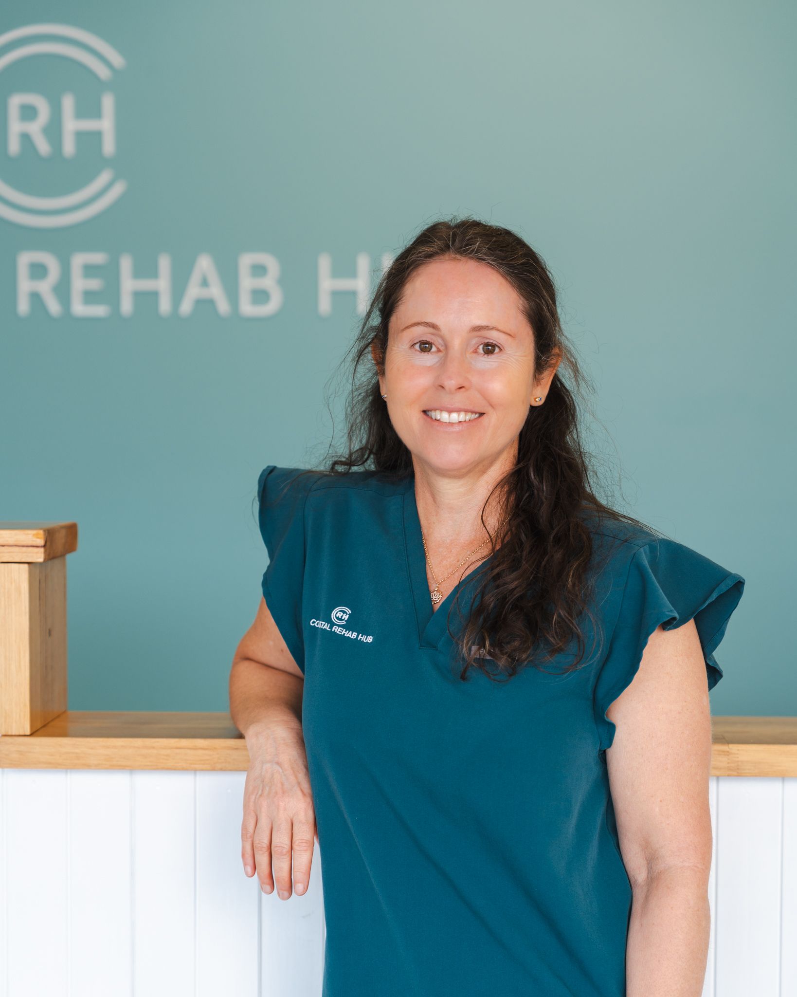 Woman in blue medical compression device, sitting in chair, talking on phone, at home.