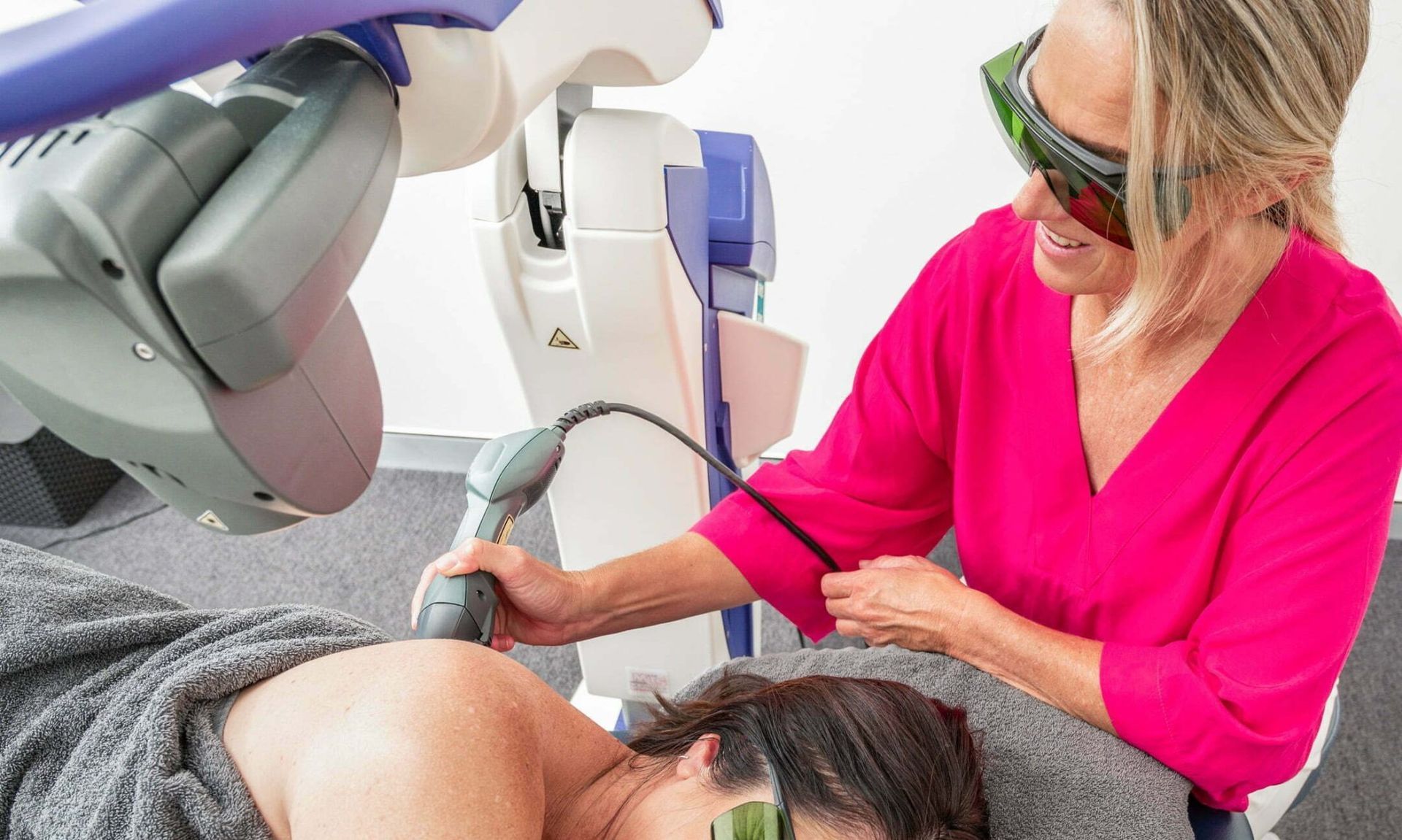Exterior view of a laser clinic with glass doors and a sign. Two chairs sit outside.