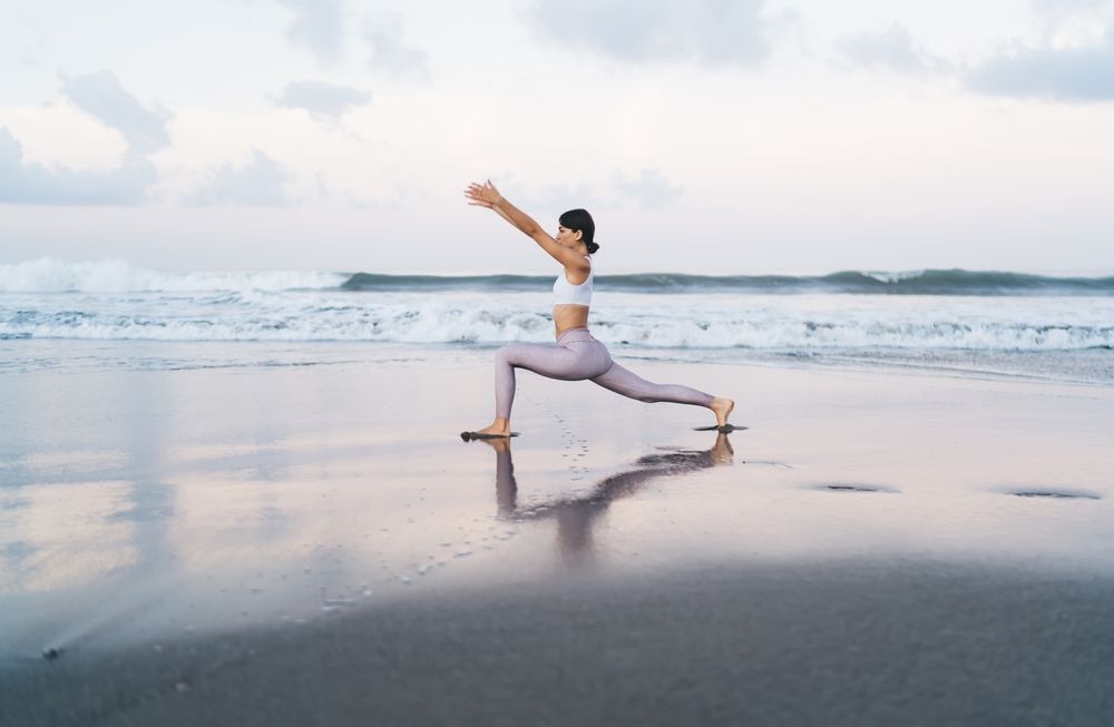 Woman in workout clothes at a reception desk, talking to a staff member. Light, airy setting.
