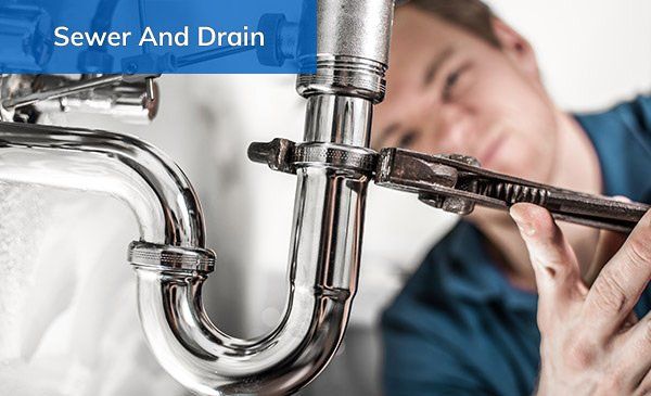 A plumber uses a wrench on the pipes to tighten a fitting.