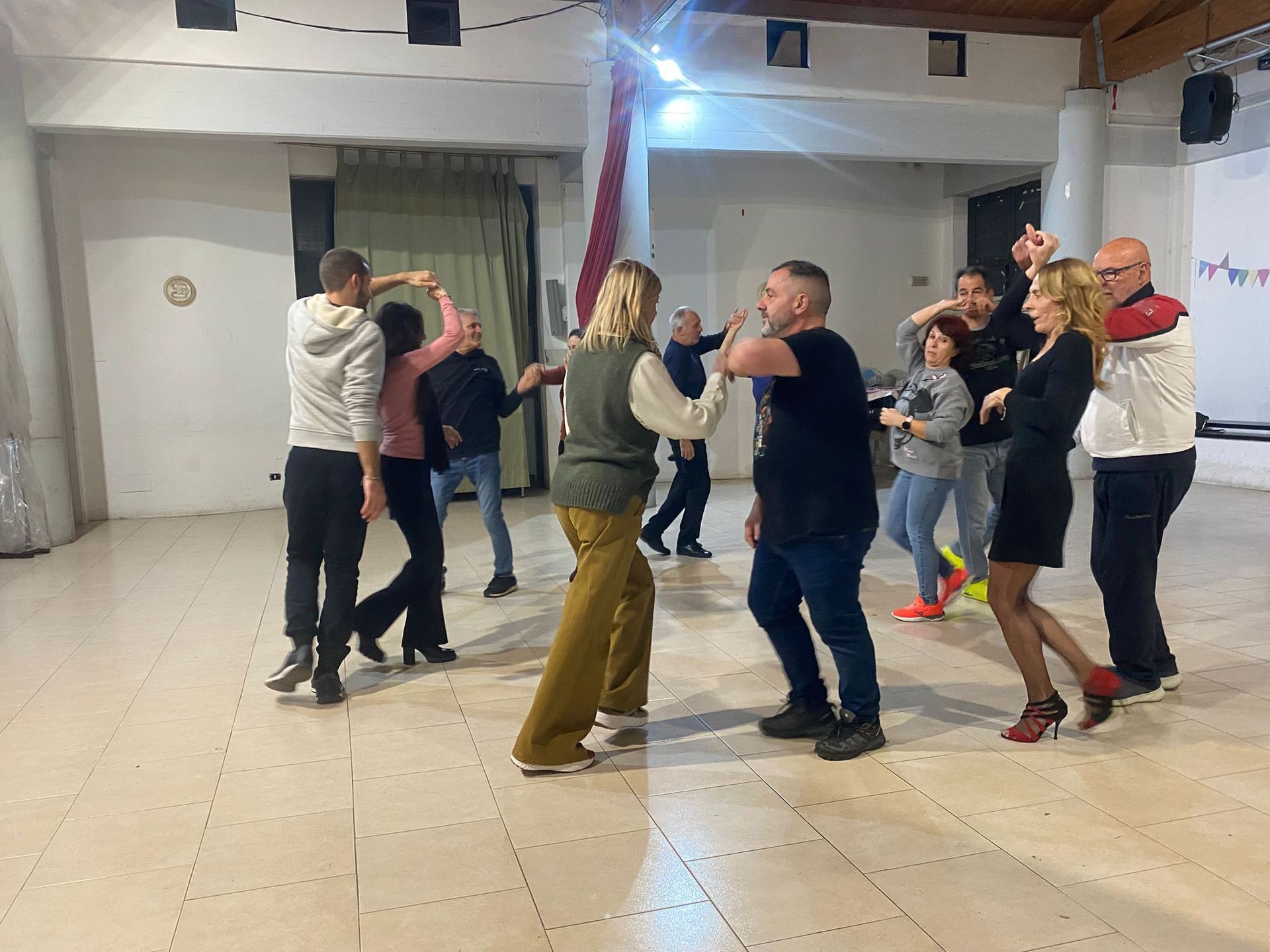 Cuoco in camice bianco e grembiule a righe, mentre mescola il cibo in una padella con un mestolo in cucina.