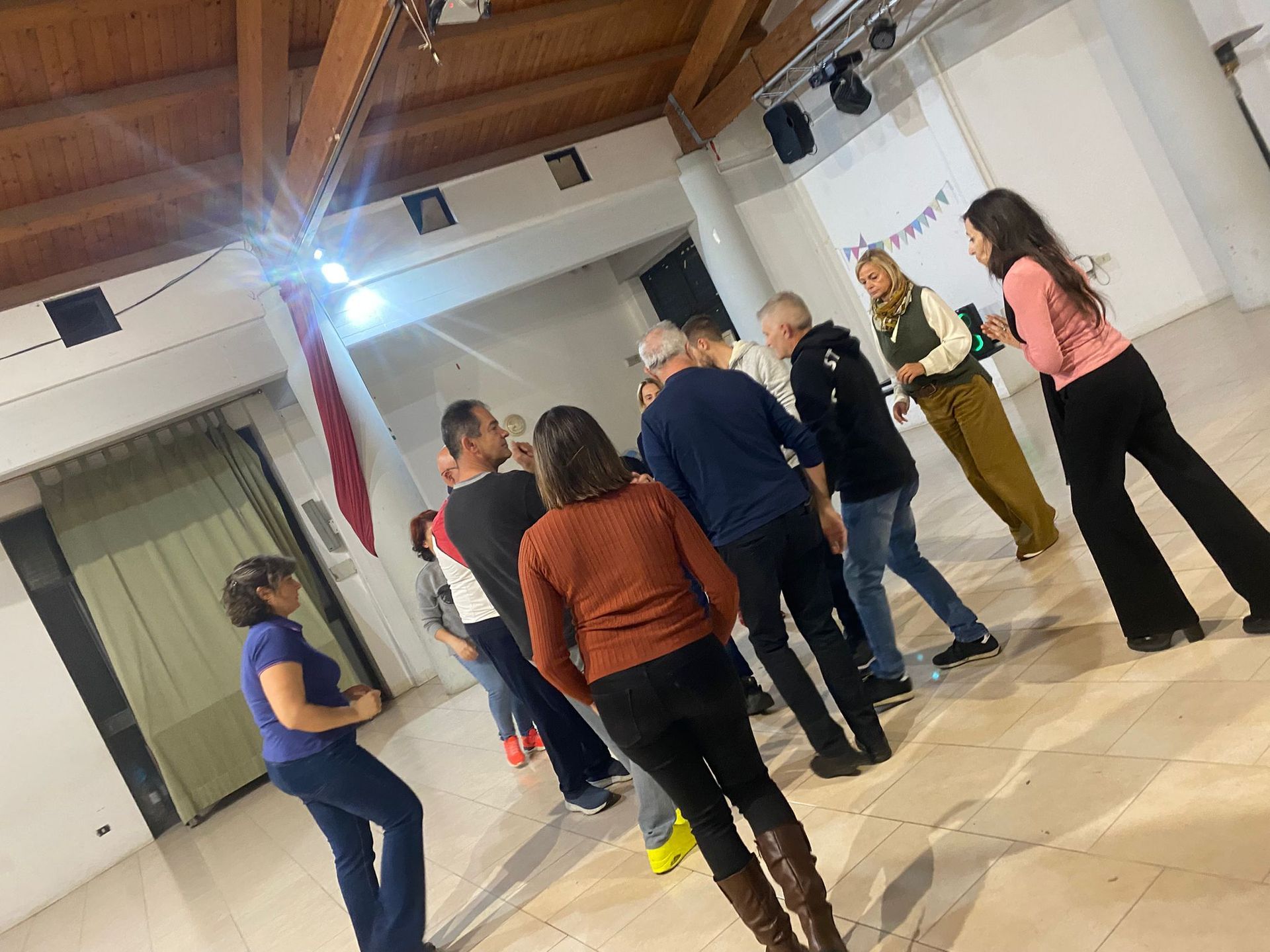 La gente balla in una stanza con un soffitto in legno e un faretto.