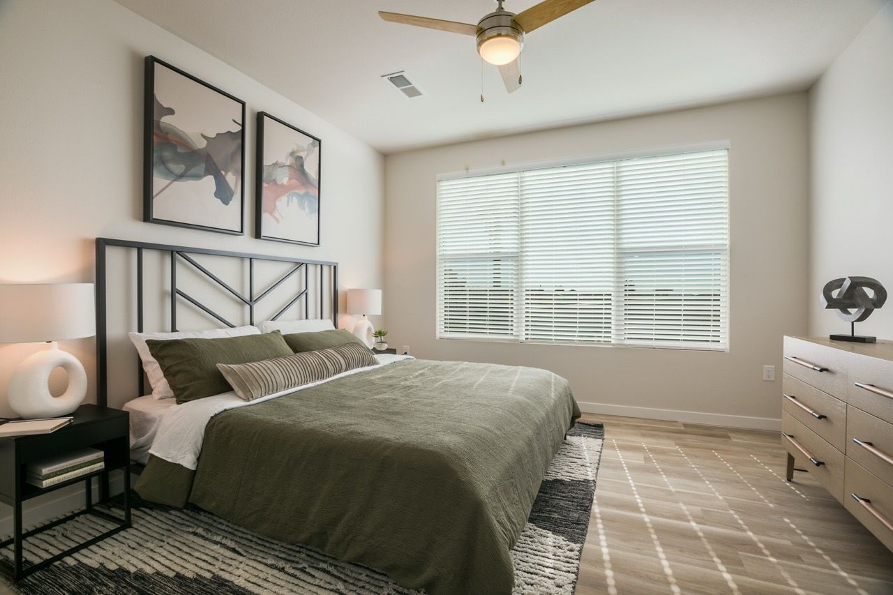 Bedroom with a queen bed, two nightstands, dresser, ceiling fan, and a large window with blinds.