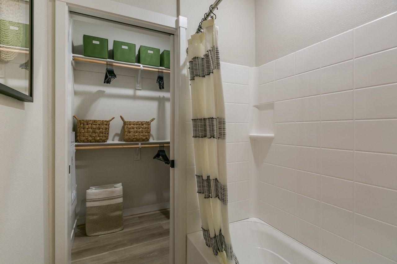 Bathroom with tub/shower and an open closet with baskets and green storage boxes.