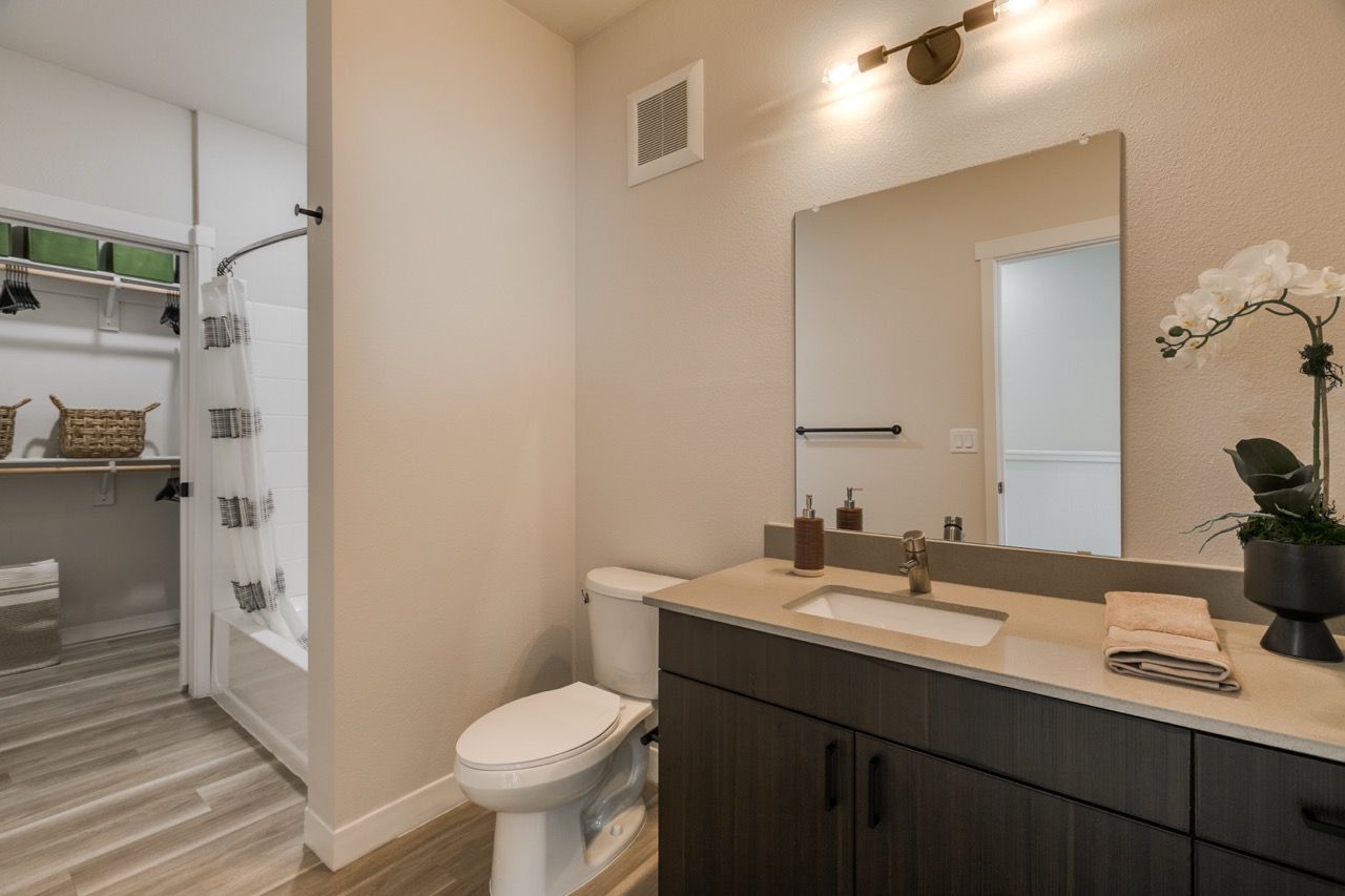 Bathroom with vanity, mirror, toilet, and shower/tub in a modern apartment unit.