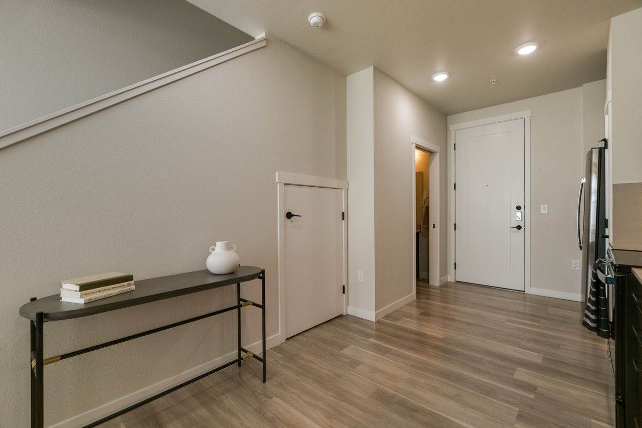 Entryway of a modern apartment with a console table, stairs along the wall, and a front door.