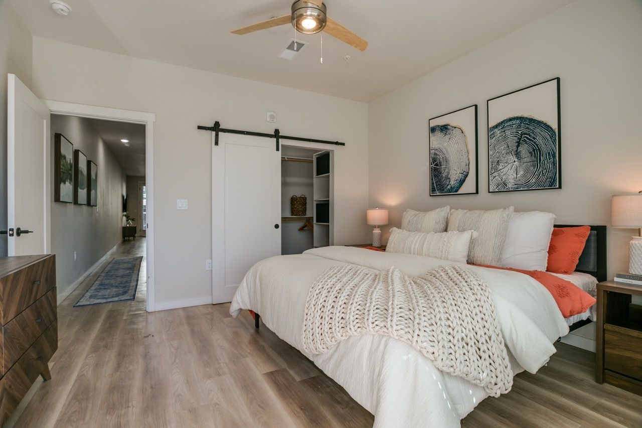 Bright bedroom with a large bed, white bedding, two nightstands, and a sliding-door closet.