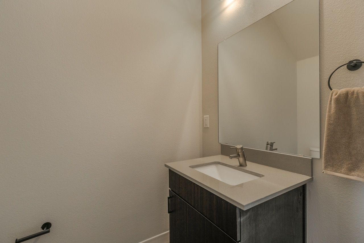 Bathroom vanity with sink, faucet, large mirror, and towel ring.