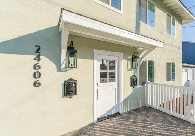 Light green two-story building with white door, awning, and address 24606 on the left.