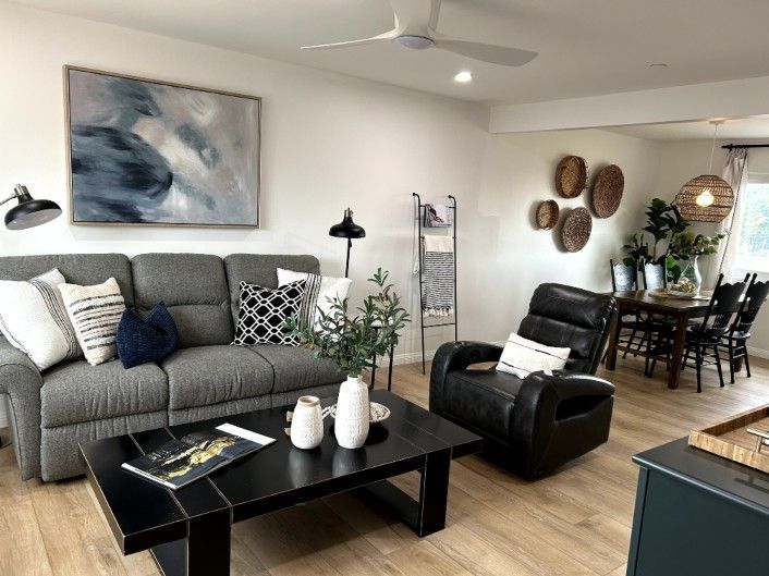 Living room with gray sofa, black recliner, artwork, and dining area.