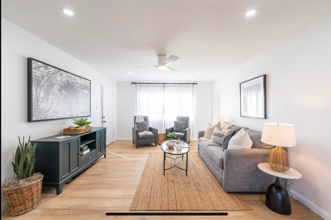 Modern living room: gray sofa, blue cabinet, two armchairs, neutral rug, light wood floor, white walls.