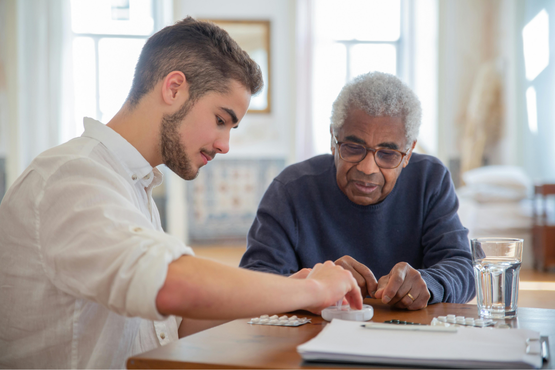 Young person helps older person with medication. Short-term assisted living options in Lomita, CA.