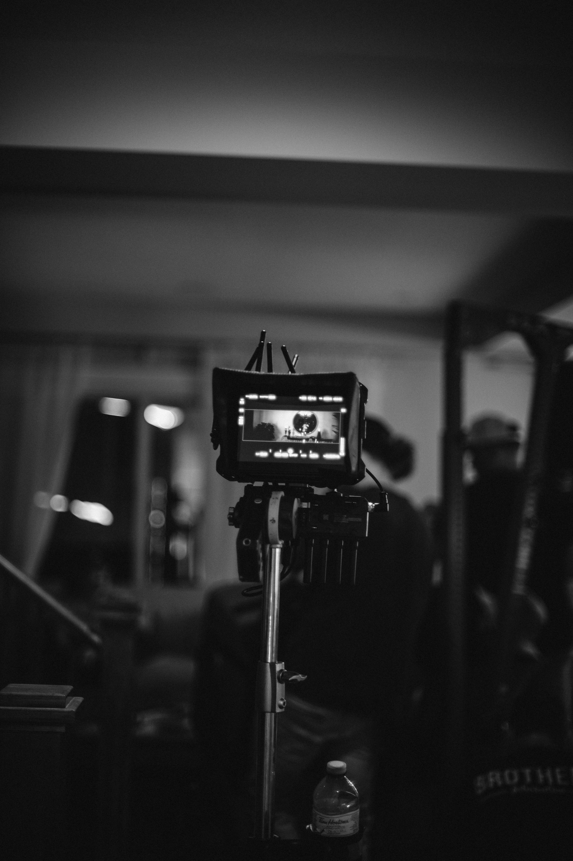 A black and white photo of a camera on a tripod.