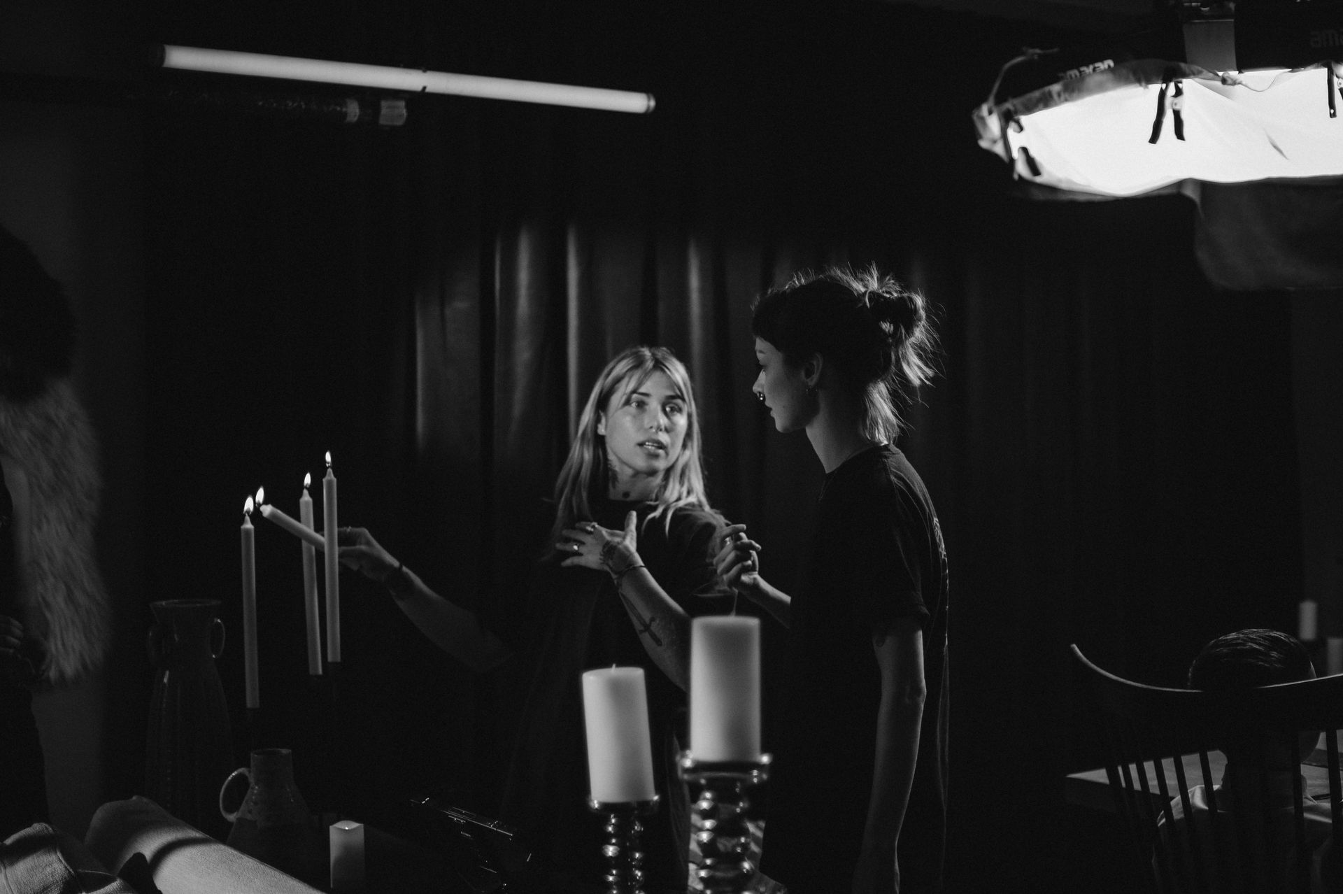 Two women are standing next to each other in a dark room with candles.