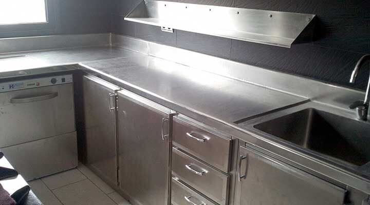 Encimera de cocina de acero inoxidable con gabinetes, fregadero y lavavajillas.