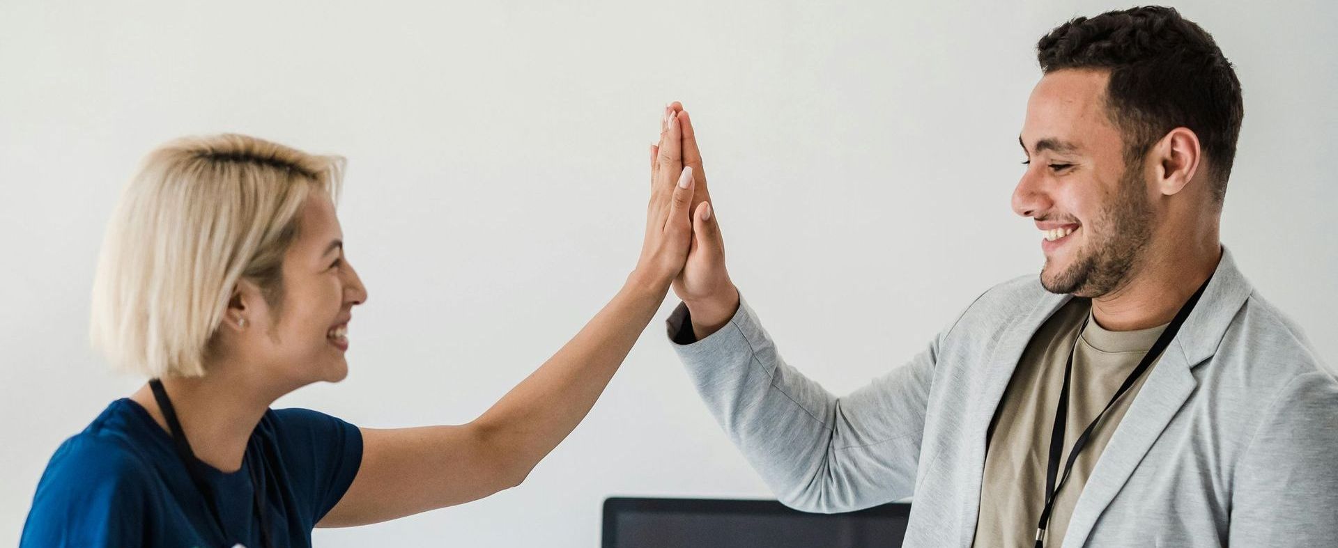 Two employees high-fiving, symbolizing the convergence of East and West.