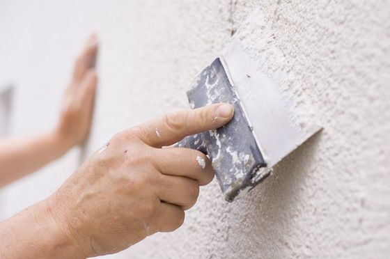Hands plastering a wall
