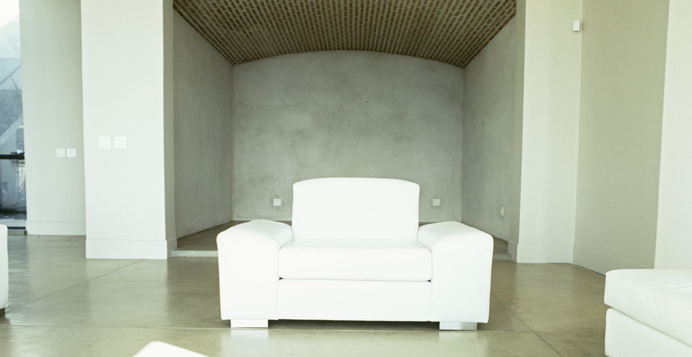 Big white chair in front of a concrete wall