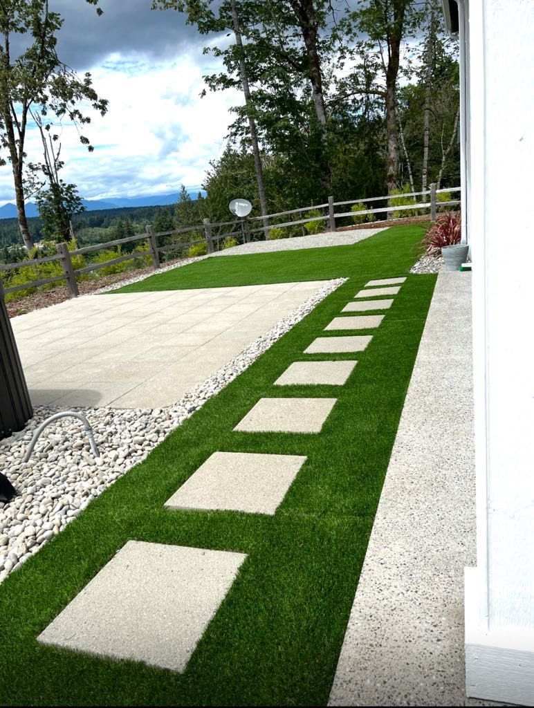 A lawn with stepping stones and a fence in the background