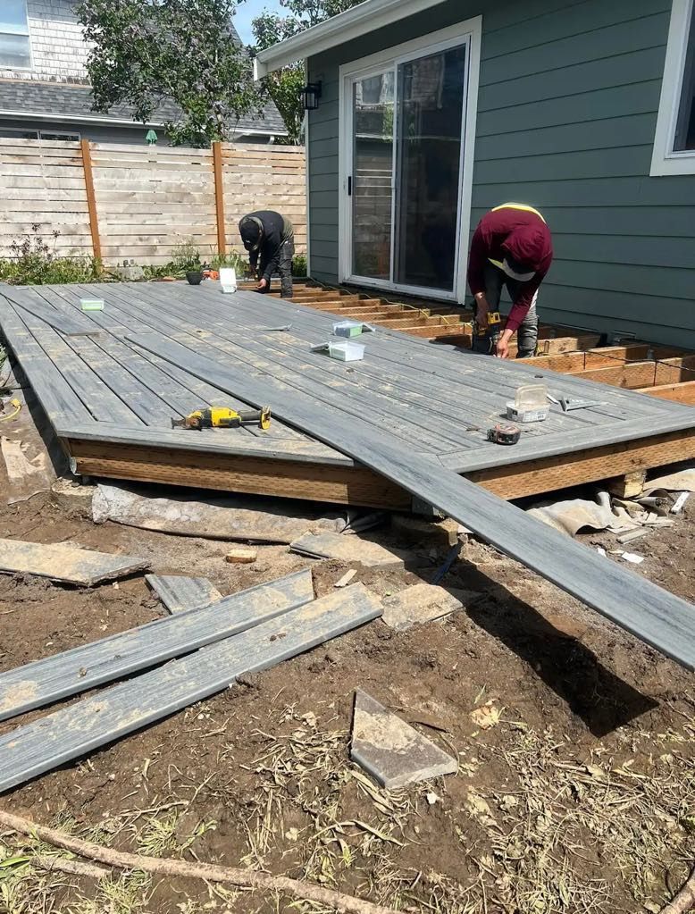 A man is working on a wooden deck in front of a house.