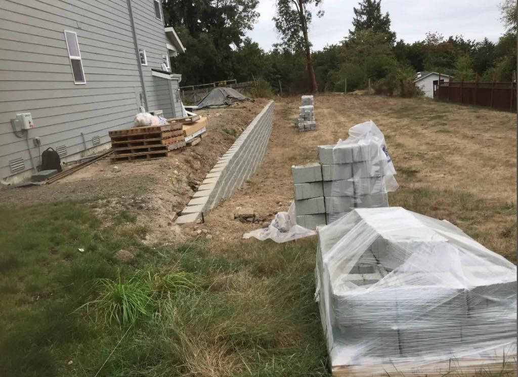 A brick wall is being built in the backyard of a house.