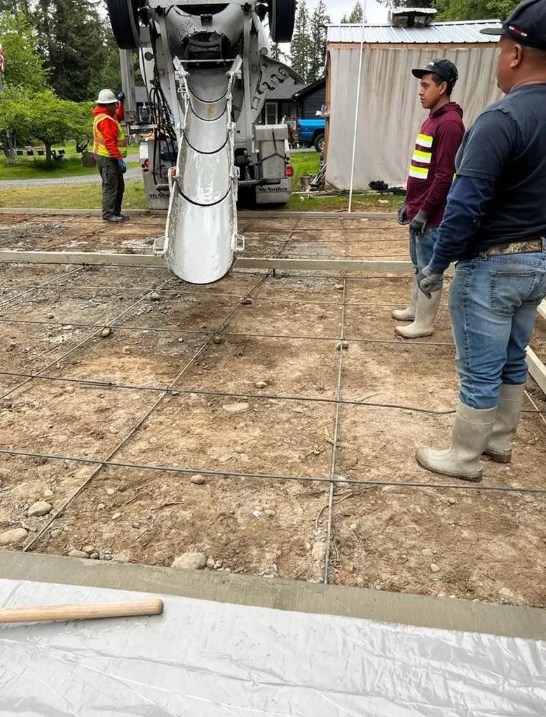A group of construction workers are standing in front of a concrete mixer.